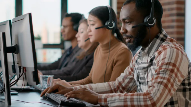 African american man working at call center office to help people with telemarketing assistance. Male employee using headphones and microphone at customer care service. Tripod shot.